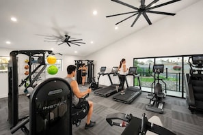 A gym with treadmills, weight machines, and a ceiling fan.