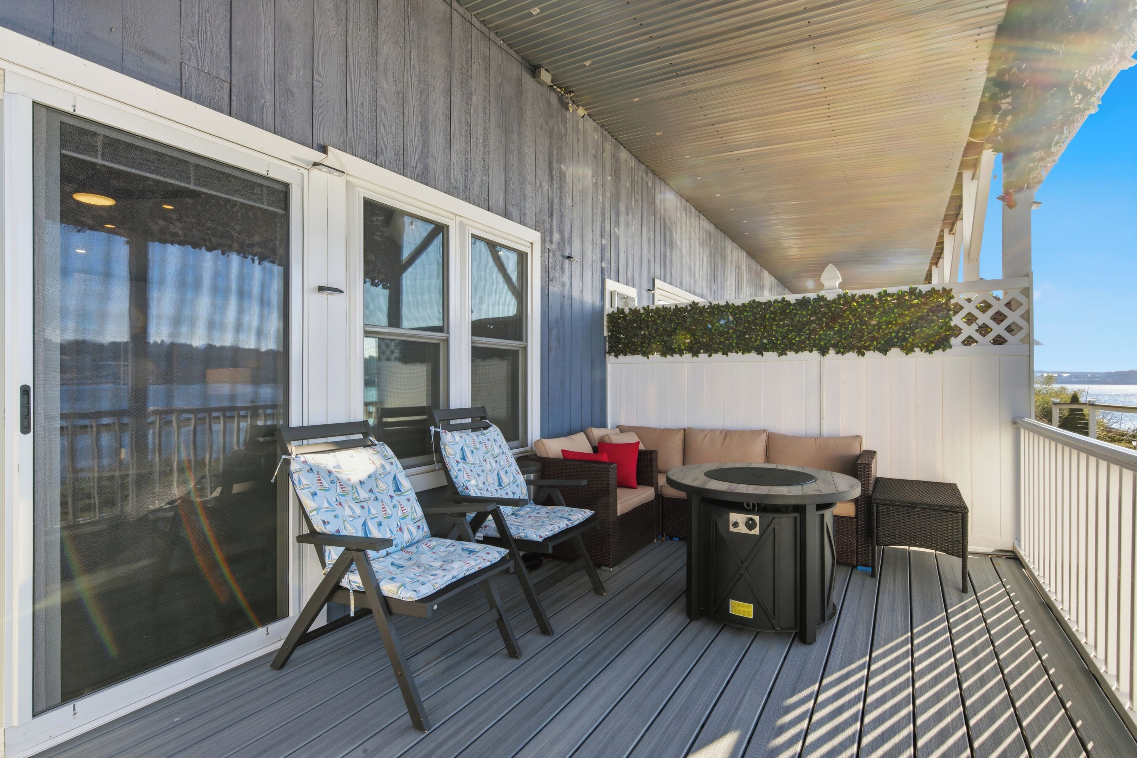 A covered outdoor deck with a sofa, two chairs, and a table.