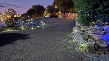 A paved pathway leading to a stone wall with a small water feature on the left.