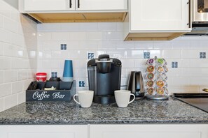 A kitchen with a coffee maker, two white mugs, a coffee bar sign, and a coffee pod holder. - Riverview Retreat: Guest Suite (Groton)