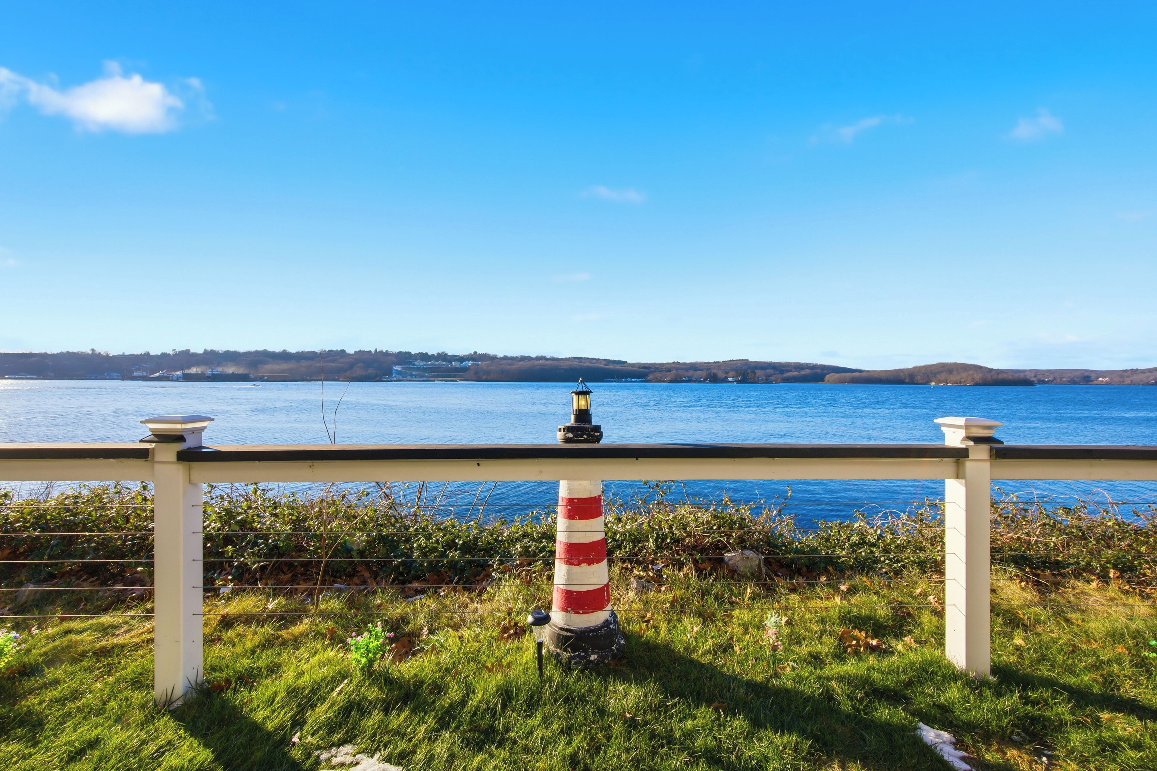 Une vue sur la côte, avec un phare, une zone herbeuse et un ciel bleu dégagé.