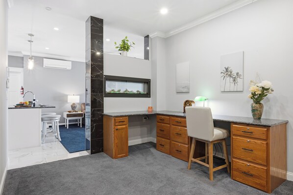 Una cocina moderna con estufa integrada, una zona de comedor con mesa y sillas blancas, y una pequeña isla con fregadero.