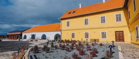 A courtyard with a yellow building, a white building, and a paved walkway.