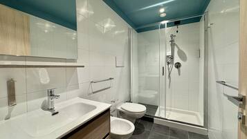 Ein modernes Badezimmer mit einer Duschkabine aus Glas, einem weißen Waschbecken und einer Toilette.