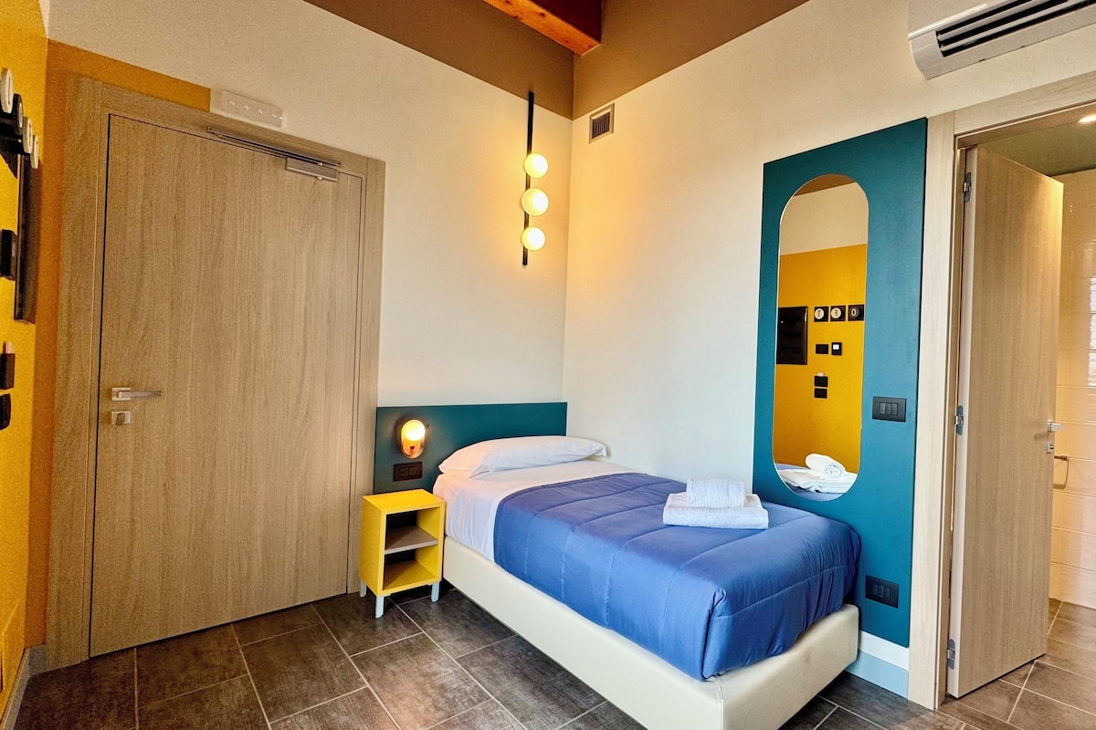 A hotel room with a bed, a nightstand, a mirror, and a wardrobe.