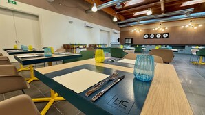 A hotel dining area with tables set for meals, chairs, and a wall with the letters "LOFT". - HC Hotel Manerbio Loft (Manerbio)