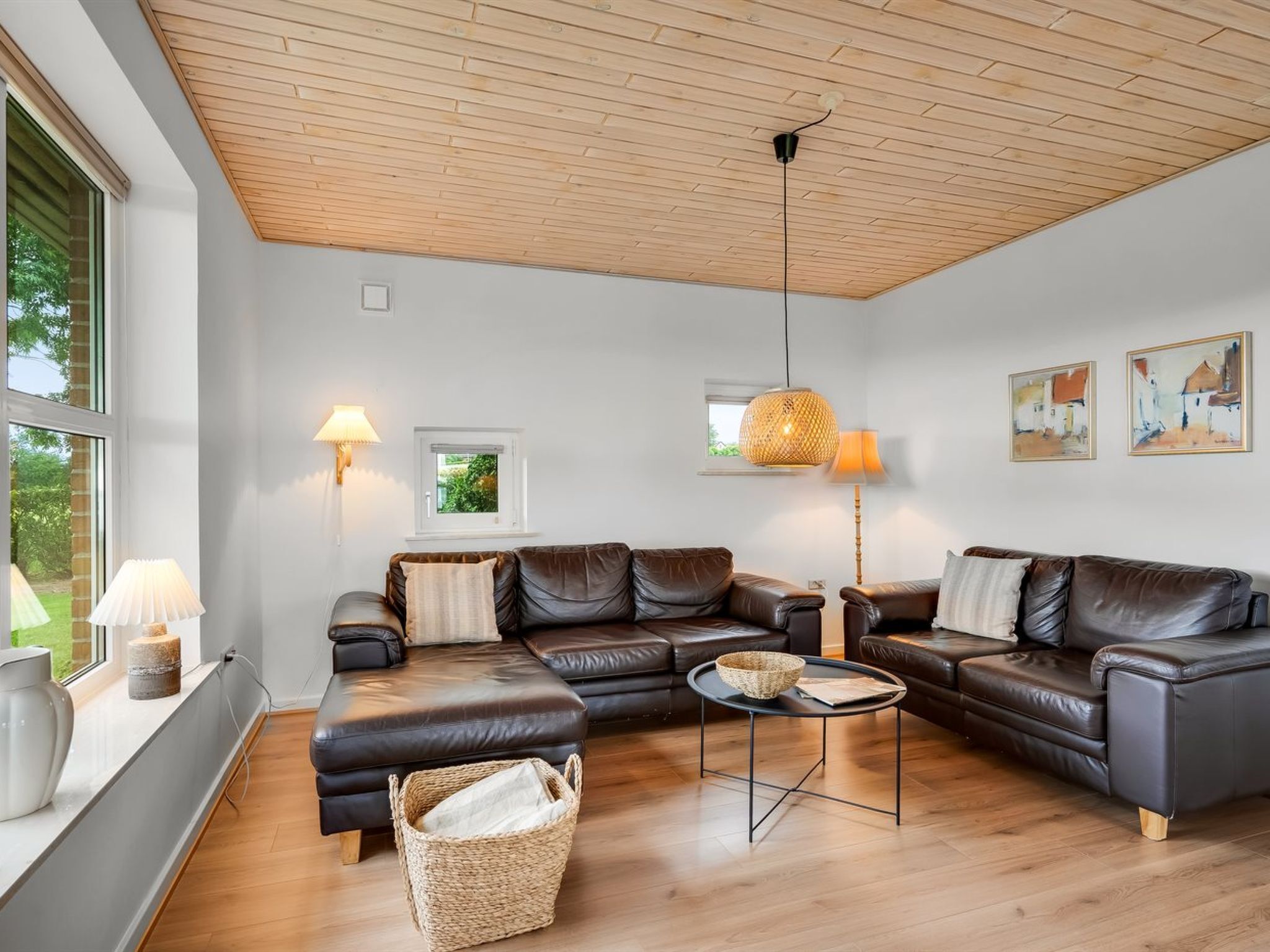A modern living room with a sectional sofa, a round coffee table, and a large window providing natural light.