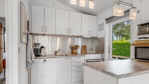 Una cocina moderna con armarios blancos, horno integrado y una isla grande con encimera de granito.