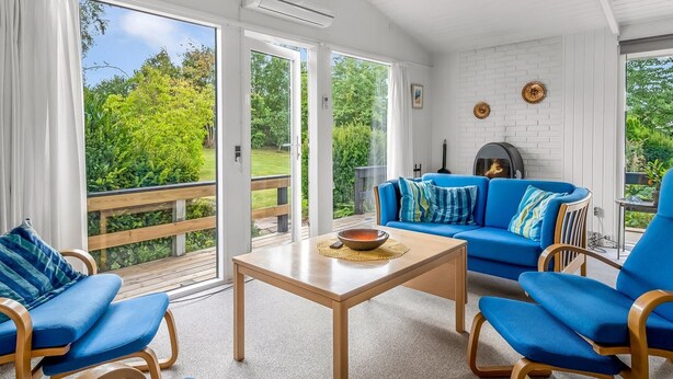 Una sala de estar moderna con un sofá azul, sillas de madera, una mesa de madera y una chimenea.
