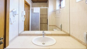A bathroom with a sink, mirror, towel rack, and a shower door. - Hotel Razlog (Razlog)