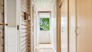 A hallway with wooden walls, a white door at the end, and a view of greenery outside. - "Ilwith" - 400m from the sea by Interhome (Børkop)