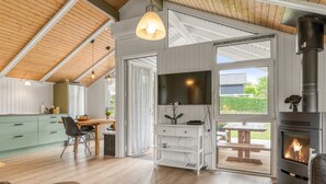 A modern interior with a wooden ceiling, a fireplace, a TV, and a dining area.