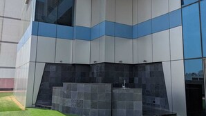 A modern building with a flat facade, large windows, and a small outdoor area with artificial grass. - Oceanview apartment with FREE parking in Hoora Manama (hoora manama)