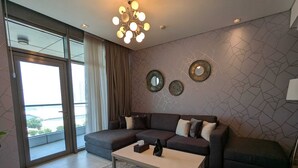 A modern living room with a sectional sofa, a coffee table, and decorative wall art. - Oceanview apartment with FREE parking in Hoora Manama (hoora manama)