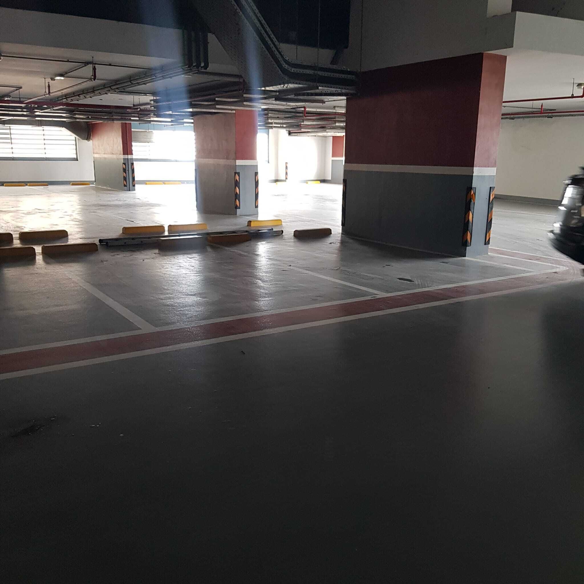 A parking garage with concrete pillars, yellow and black barriers, and a red line on the floor.