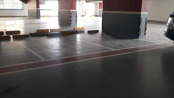 A parking garage with concrete pillars, yellow and black barriers, and a red line on the floor.