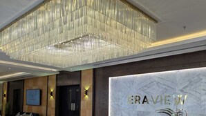 A modern lobby with a chandelier, a reception desk, and a seating area with a sofa and armchairs. - Oceanview apartment with FREE parking in Hoora Manama (hoora manama)