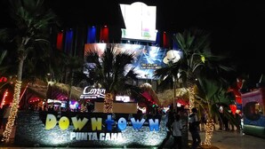 A brightly lit sign with 'Downtown Punta Cana' and 'Concierto' visible, surrounded by palm trees and festive decorations. - Luxury private Villa with Private Pool in Vista Cana Punta Cana (Punta Cana)