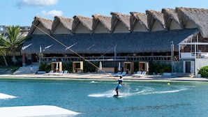 A water sports area with a thatched-roof building, lounge chairs, and a pool. - Luxury private Villa with Private Pool in Vista Cana Punta Cana (Punta Cana)