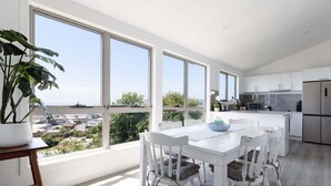 Una cocina moderna con armarios blancos, un refrigerador de acero inoxidable y un ventanal con vistas a un paisaje urbano.