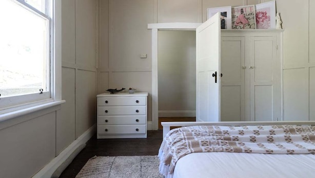 Un dormitorio con cama, cómoda, armario y ventana.