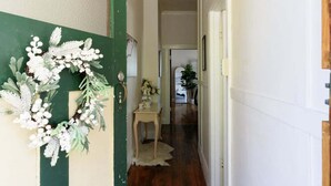 Un pasillo con una puerta verde, pared blanca y suelo de madera.