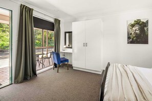 A hotel room with a bed, a desk, a chair, and a large wardrobe.