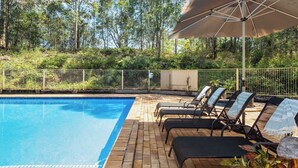 Une piscine avec des chaises longues et un parasol.