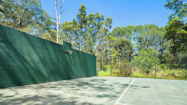 An outdoor tennis court with a green wall and trees in the background. - Quiet Hinterland Studio near Robina (Mudgeeraba)