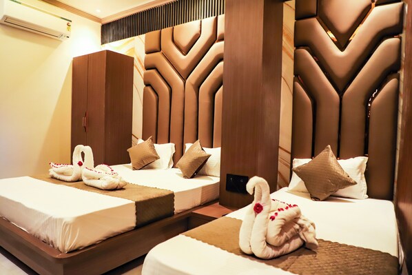 Habitación de hotel con dos camas, cada una con cabecera, armario y adornos con forma de cisnes en las camas.