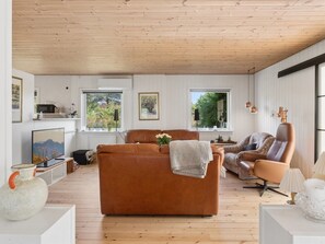 A modern living room with a brown leather sofa, a patterned armchair, and a television.