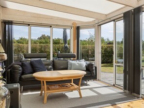 Ein modernes Wohnzimmer mit einer Couch, einem Holztisch und einer großen Glasdoor, die zu einem Außenbereich führt.