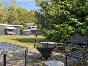 An outdoor patio area with a swing set, a metal table, and a metal chair.