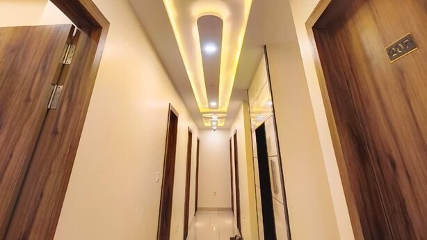 A hotel hallway with a modern ceiling design, wooden doors, and a clean, tiled floor. - Hotel Vistara (Ujjain)