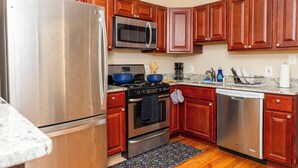A kitchen with wooden cabinets, stainless steel appliances, and a granite countertop. - 3BR•4 Bath•2-Min Walk to Johns Hopkins Hospital. (Baltimore)
