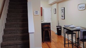 A staircase leading to a landing with a ceiling light, a dining area with a table and chairs, and a kitchen area with a sink and cabinets. - 3BR•4 Bath•2-Min Walk to Johns Hopkins Hospital. (Baltimore)