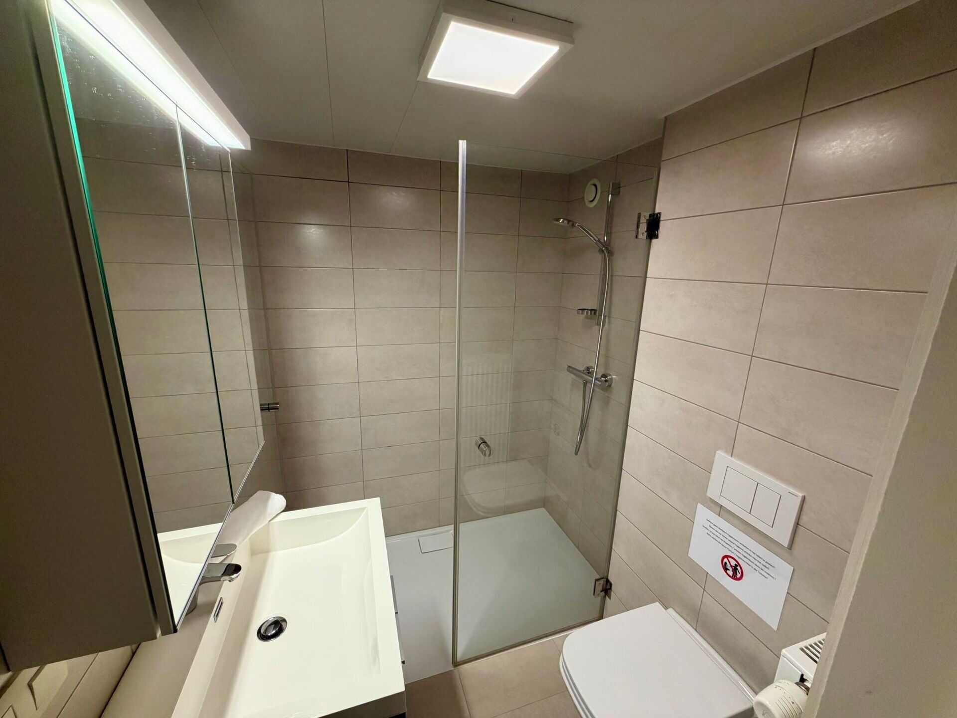 Ein modernes Badezimmer mit einer einteiligen Duschkabine, einem weißen Waschbecken und einer Toilette.