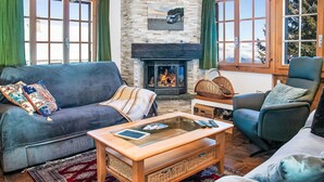 Una sala de estar acogedora con chimenea, dos sofás, una mesita de centro y vistas al exterior.