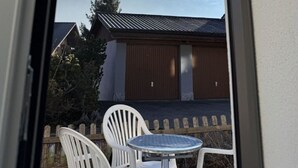 Parveke, jolta avautuu näkymä vuorille, puinen aita ja pöytä tuoleineen.