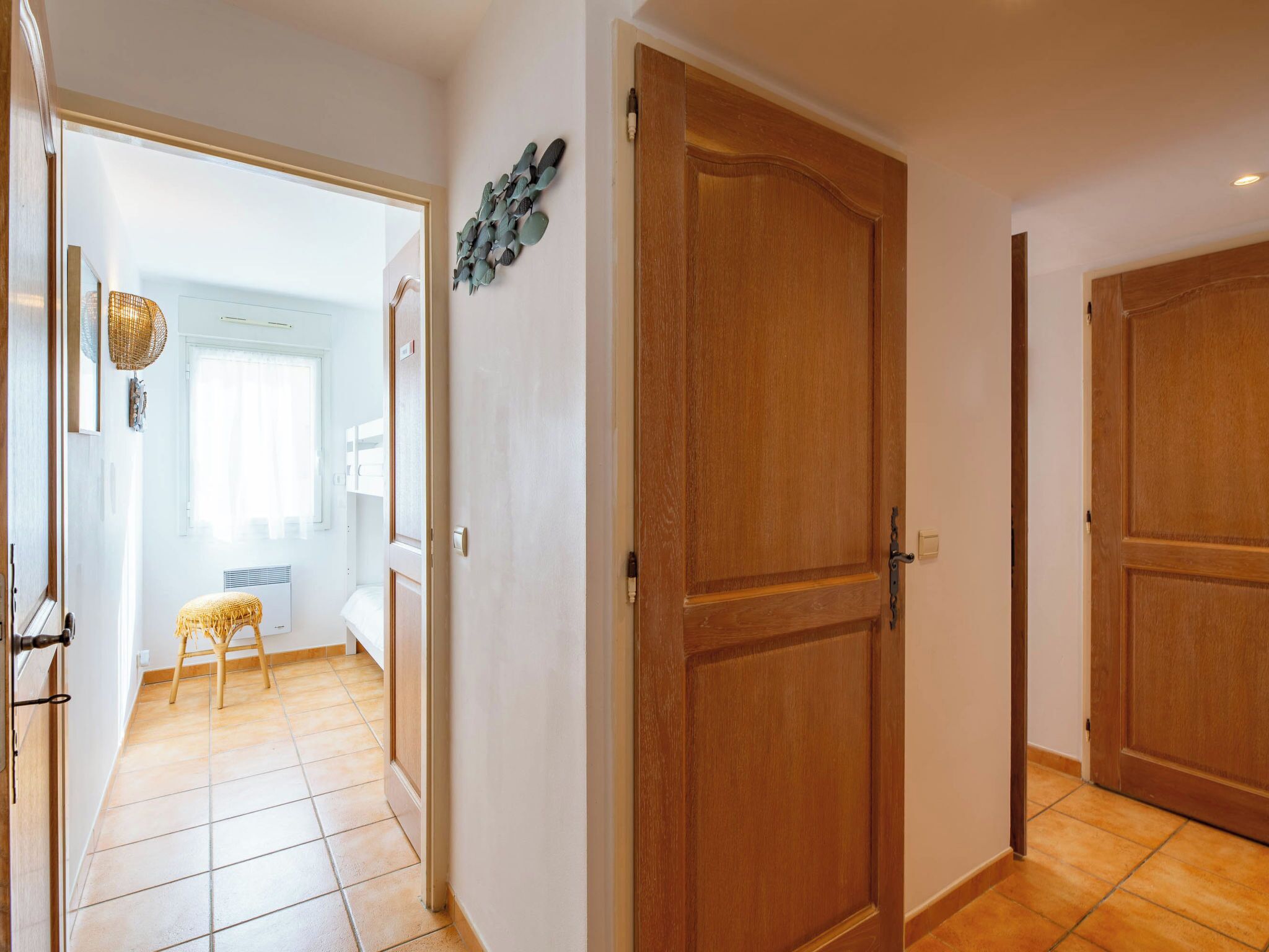 A hallway with a wooden door, a small stool, and a wall-mounted decoration.