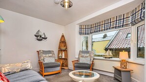 Un salon chaleureux avec un canapé, deux fauteuils, une table basse et une bibliothèque.