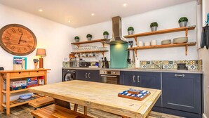 Une cuisine de taille réduite, avec une table en bois, des appareils électroménagers intégrés et une horloge au mur.