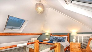 Une chambre avec un balcon en verre, un cadre de lit en bois, un lustre et une vue sur l’extérieur.