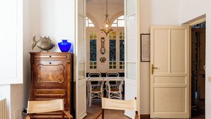Ein Zimmer mit einem Holzschrank, zwei Stühlen, einem Tisch und einer Tür zu einem anderen Raum.