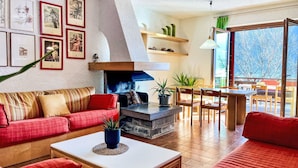 Ein Wohnzimmer mit Kamin, roten Sofas, einem Couchtisch und einem Essbereich mit Stühlen und Tisch.