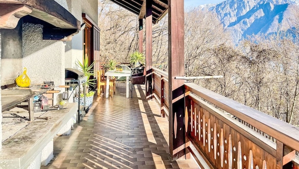 Ein überdachter Außenbereich mit Holzbalkon, Tisch und Stühlen.