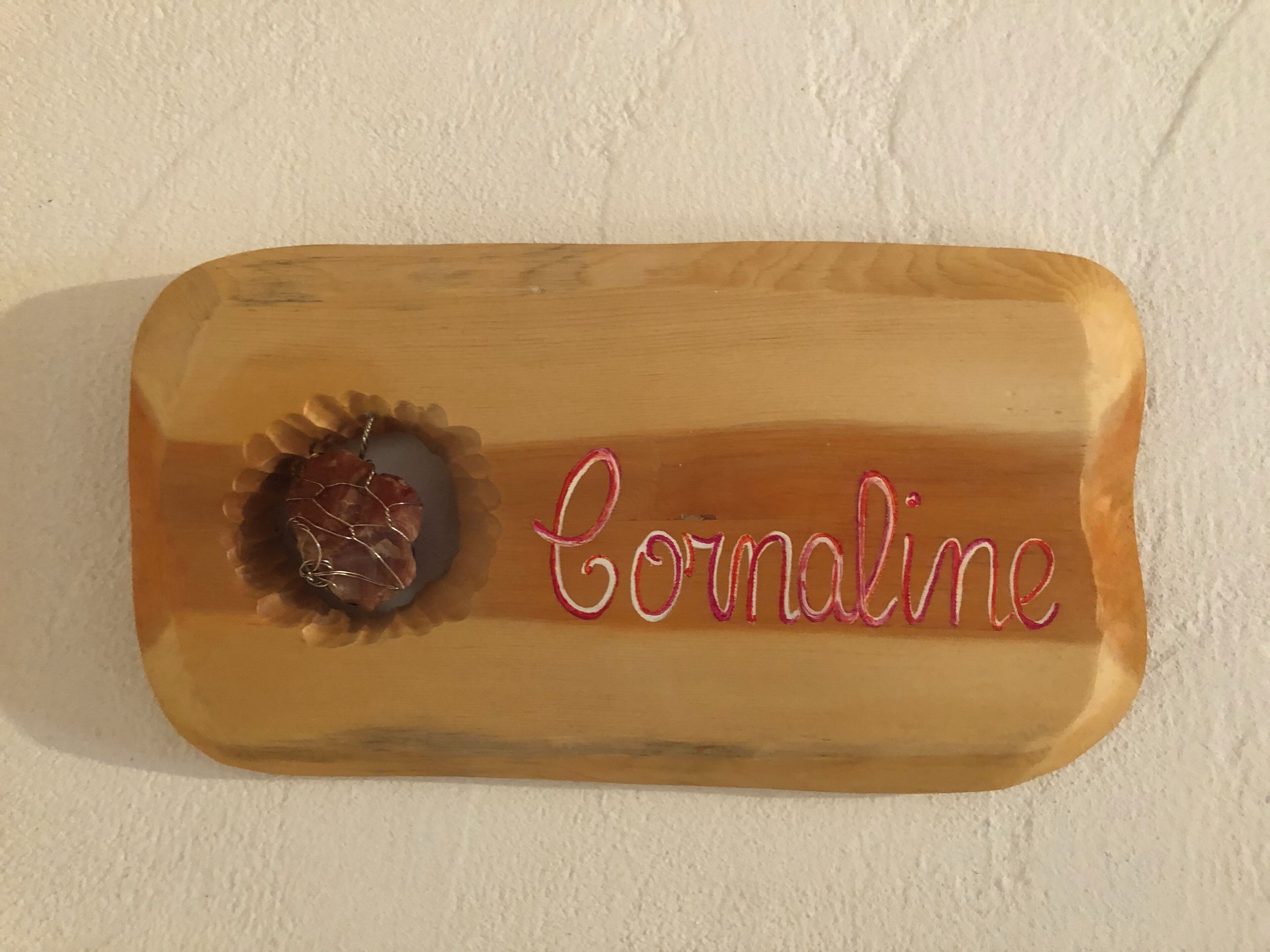 Eine Holzplakette mit dem eingravierten Namen „Coraline“.