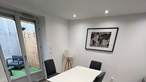 A dining area with a white table and four chairs, a floor lamp, and a framed picture on the wall. - Maison des Volcans - 3 double bedrooms - 2 bathrooms - Patio - Wifi (Ceyrat)