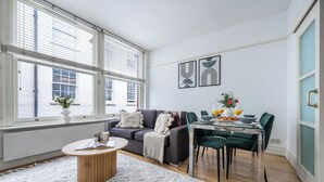 Un salon moderne comprenant un canapé, une table à manger, des chaises et une table basse.