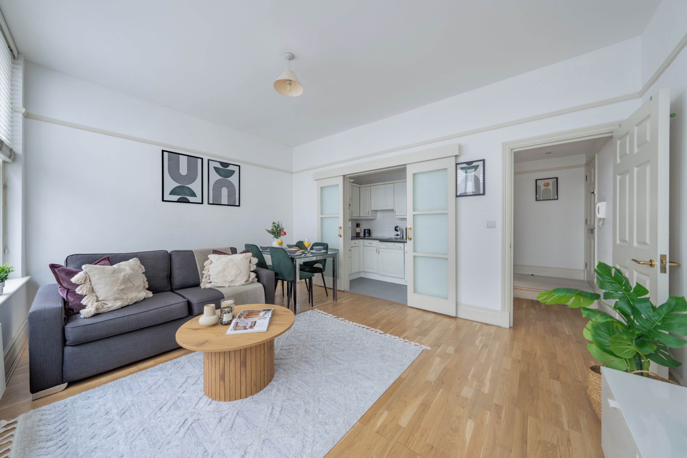 Una sala de estar moderna con un sofá gris, una mesa de centro de madera y una alfombra blanca.